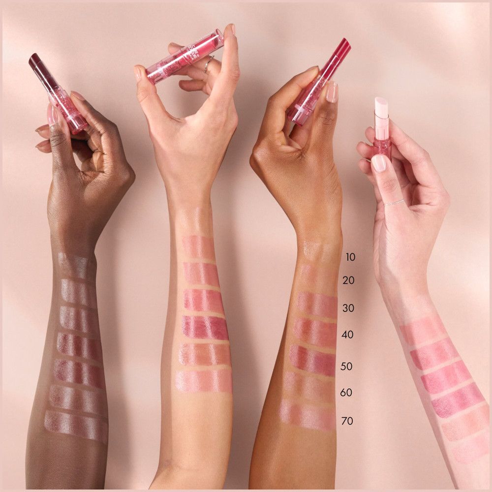 Mains avec échantillons de baume à lèvres. Différents tons de peau, échantillons de couleurs numérotés. Produit non reconnaissable.