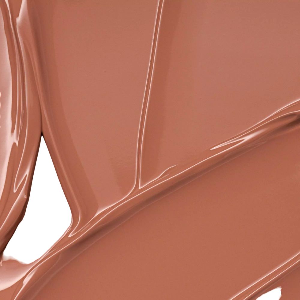 Gros plan d'une couleur de rouge à lèvres brillante et marron. La couleur est lisse et réfléchit la lumière.