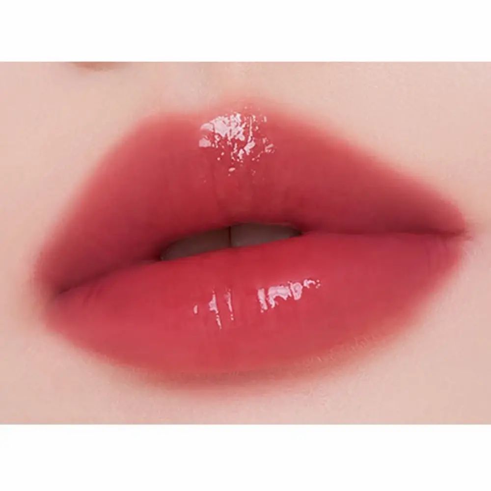 Close-up van lippen met glanzende, rode lipgloss. De lippen zijn vol en glanzend. Huid rond de lippen is zichtbaar.