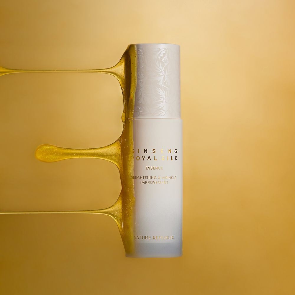 Wit flesje Ginseng Royal Silk Essence met gouden vloeistof. Gouden achtergrond.