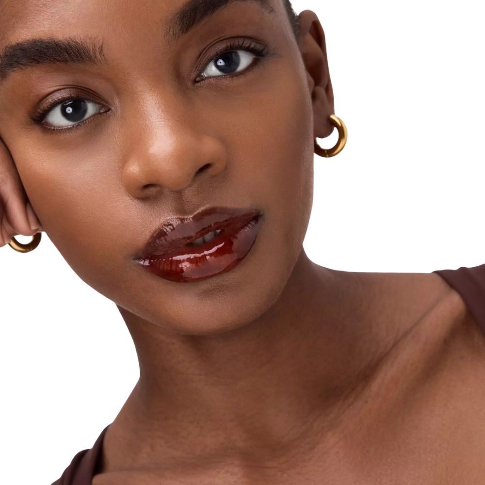Close-up van een vrouw met glanzende, rode lippen. Donkere huid. Gouden oorbellen.