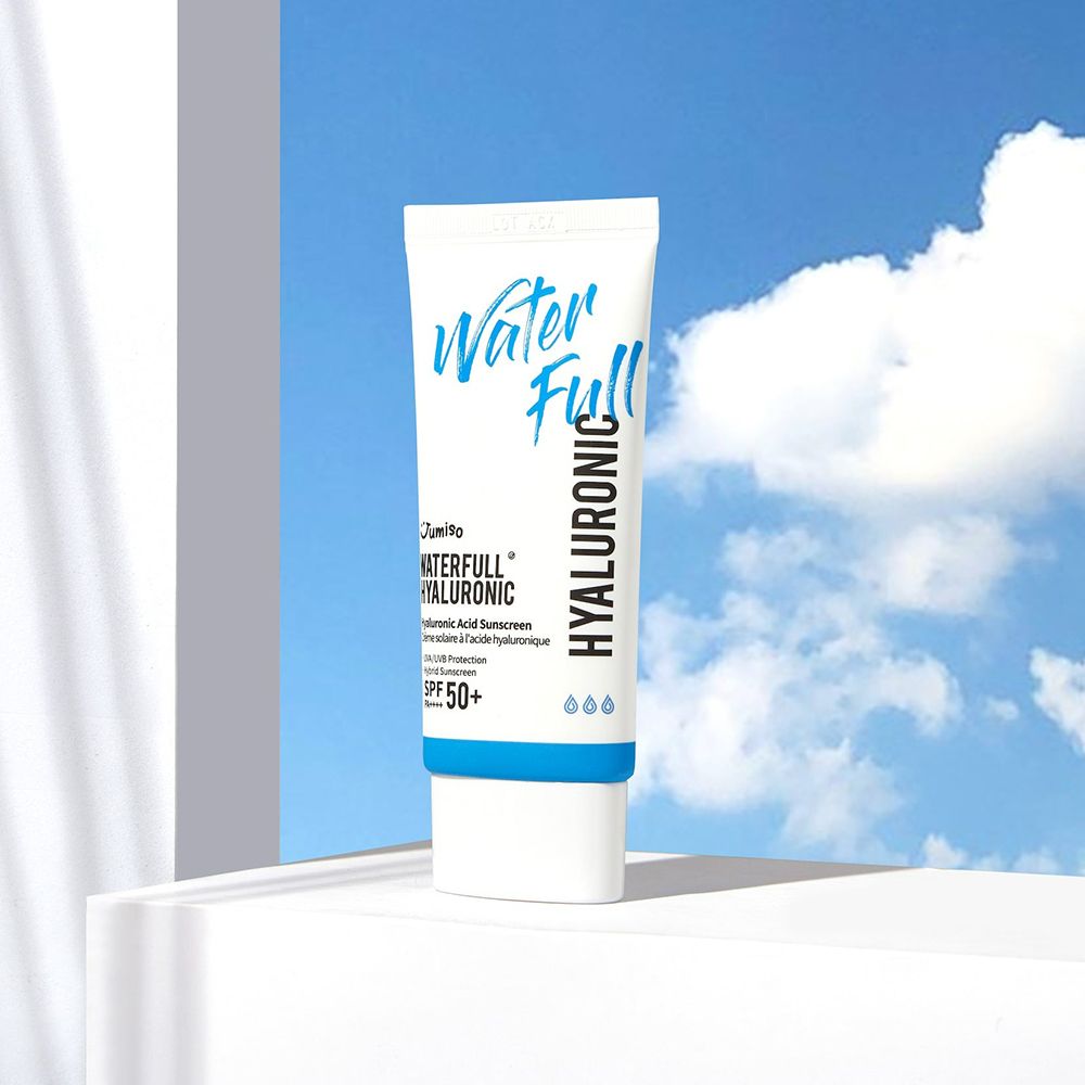 Witte tube met blauwe dop. Opschrift: Water Full, Hyaluronic, SPF 50+. Product op wit oppervlak, lucht op de achtergrond.