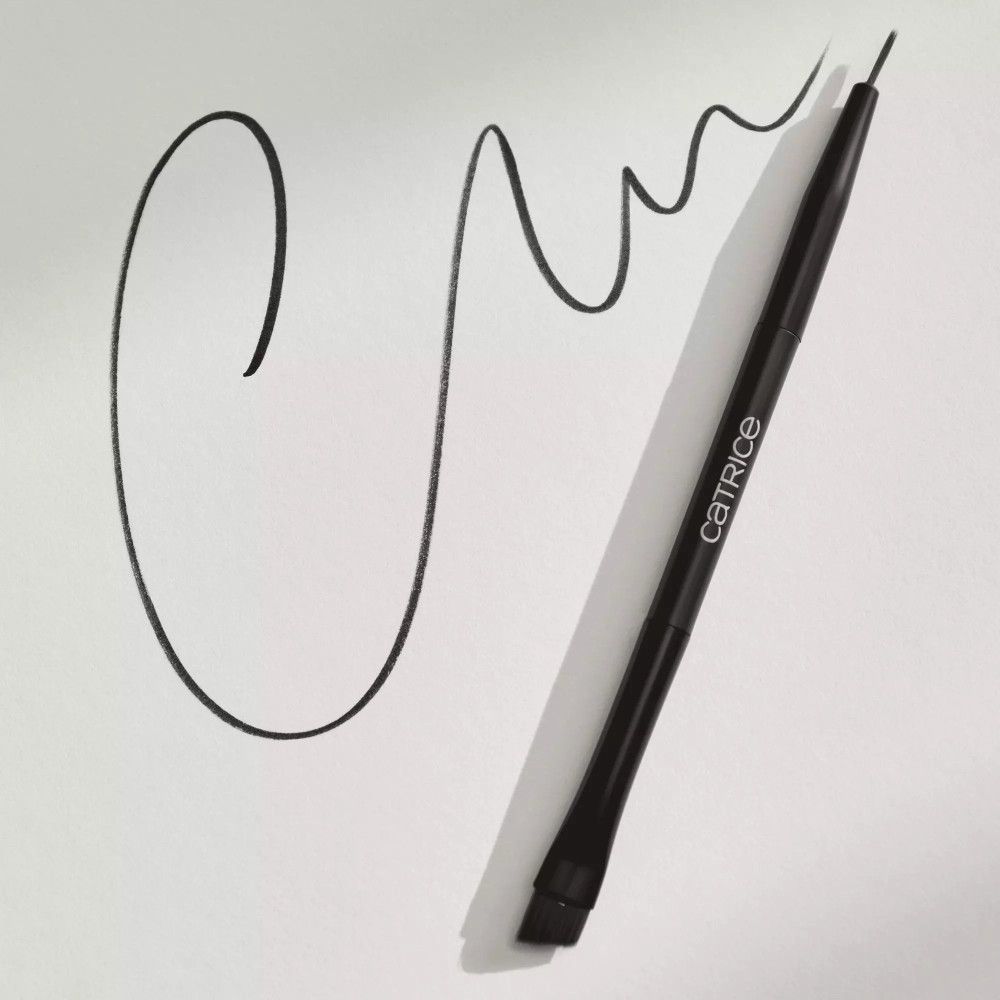 Pinceau eyeliner noir sur papier blanc. Le pinceau trace une ligne incurvée. Marque Catrice sur le manche.