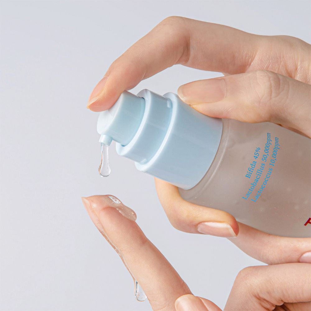 Een hand drukt een druppel vloeistof uit een fles. De druppel valt op een vinger.