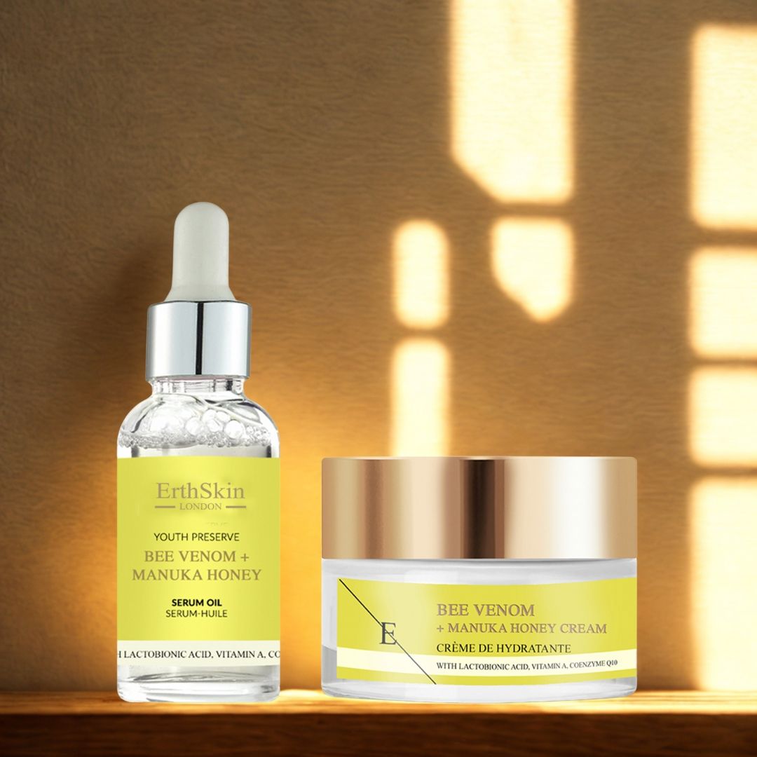 Serumfles en crème pot. Beide met gele etiketten en productnamen. Serum met pipet. Crème met gouden deksel, op hout.