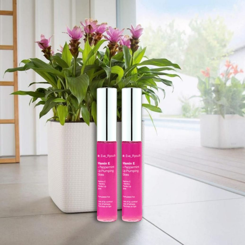 Deux flacons de Dr. Eve Ryouth Vitamin E Lip Plumping Gloss à côté d'une plante.