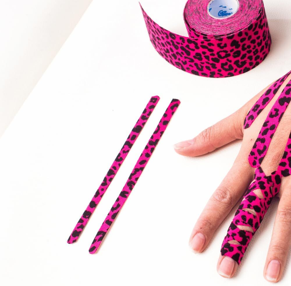 Roze kinesiotape met luipaardprint op vingers en een rol. Twee gesneden strips liggen ernaast.