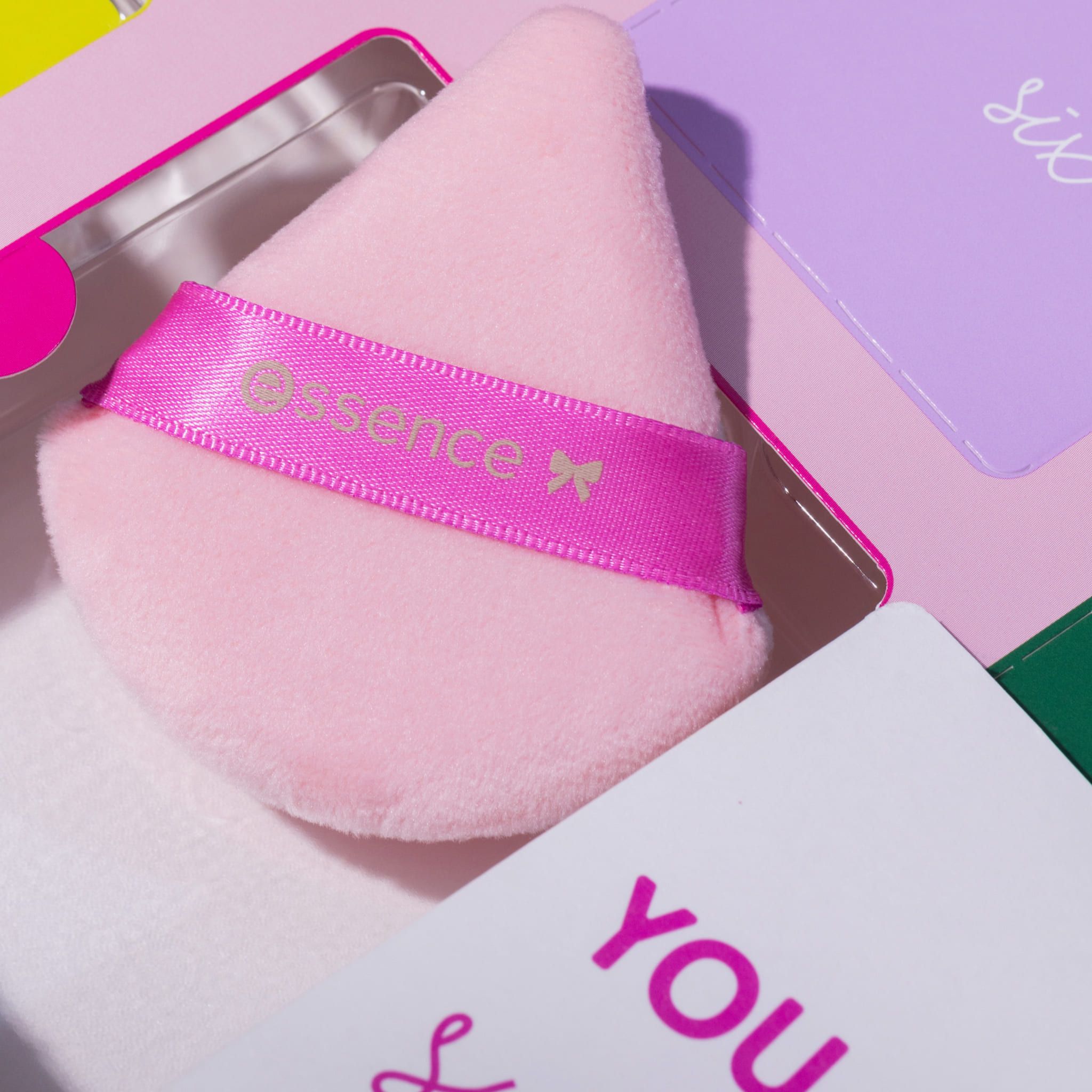 Éponge de maquillage Essence. Éponge rose avec ruban rose. Inscription noire.