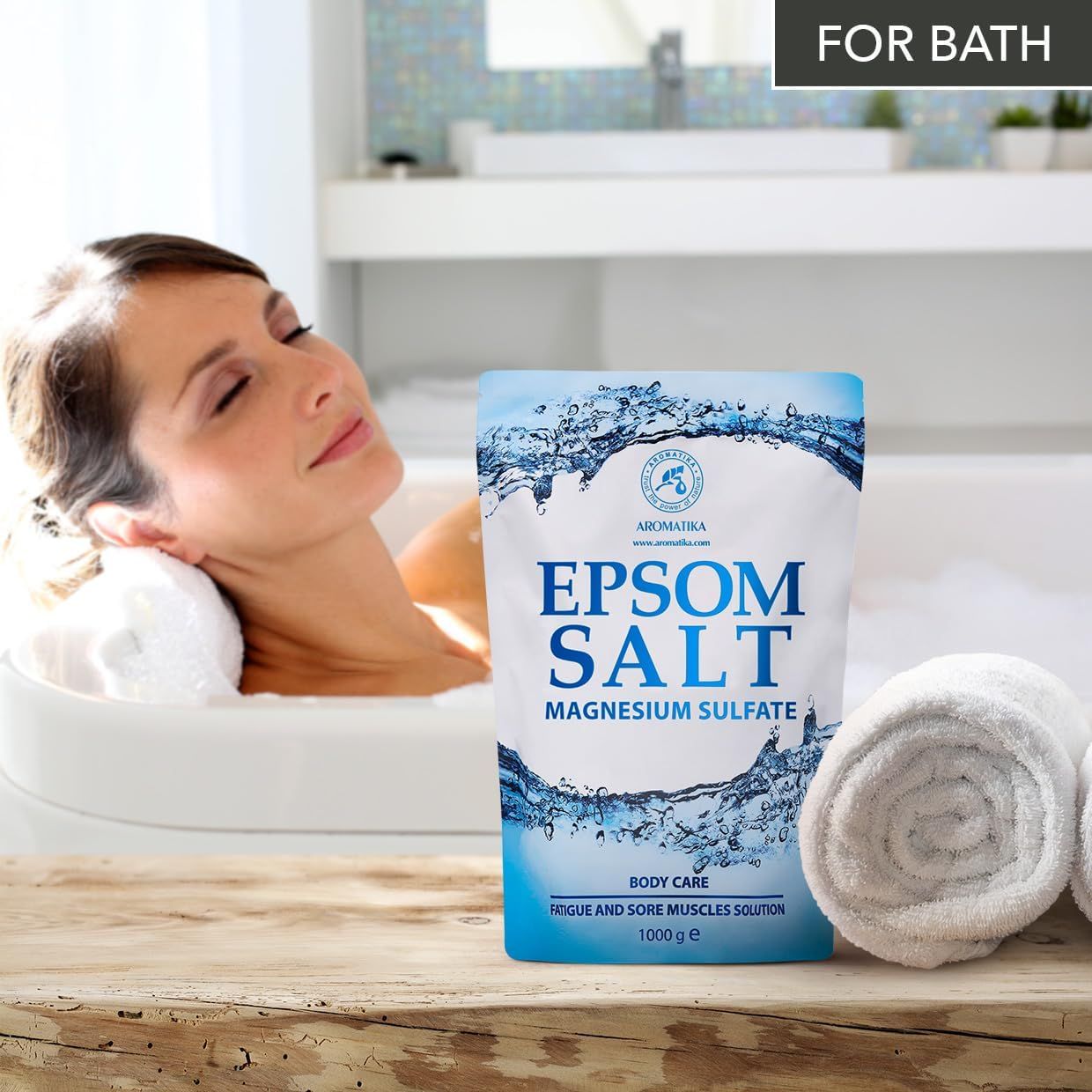 Femme se détendant dans une baignoire à côté d'un sachet de sel d'Epsom AROMATIKA.