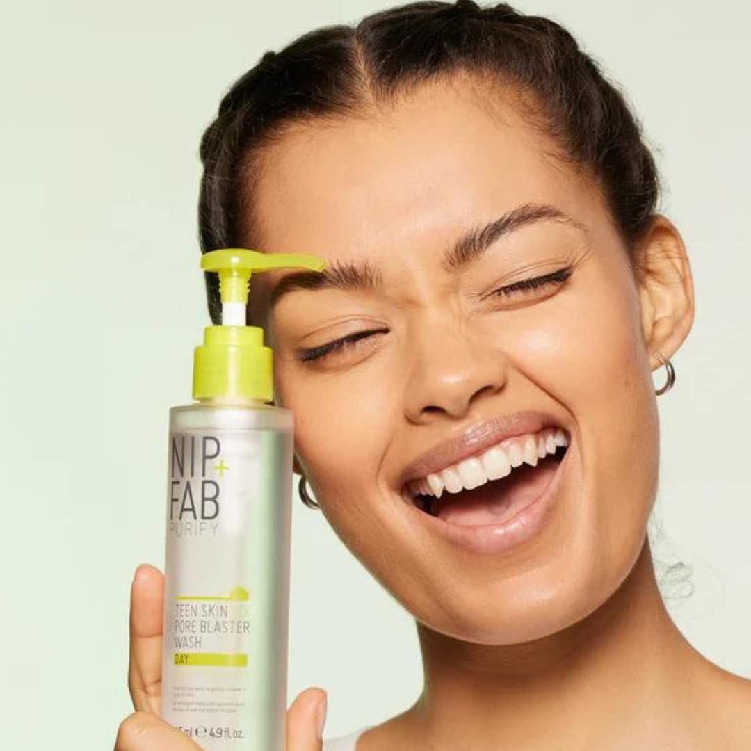 Femme tenant Nip + Fab Teen Skin Fix Pore Blaster Wash. Flacon avec pompe. Accents jaunes. La femme sourit.