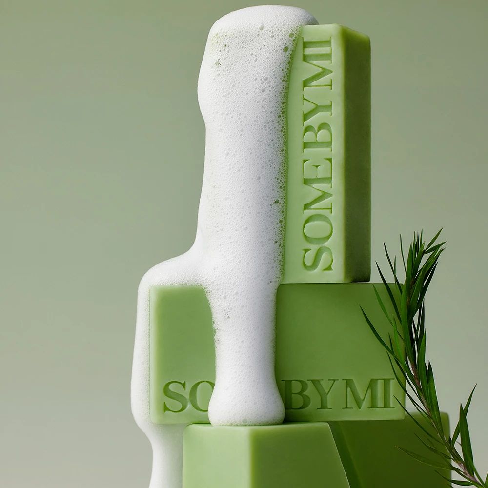 Groene stukken zeep met schuim. De tekst SOME BY MI is zichtbaar. De stukken zeep zijn opgestapeld.