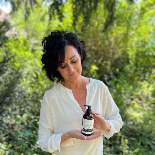 Femme tenant un flacon. Flacon avec texte: Repairing Silky Body Lotion. Flacon brun avec pompe noire.