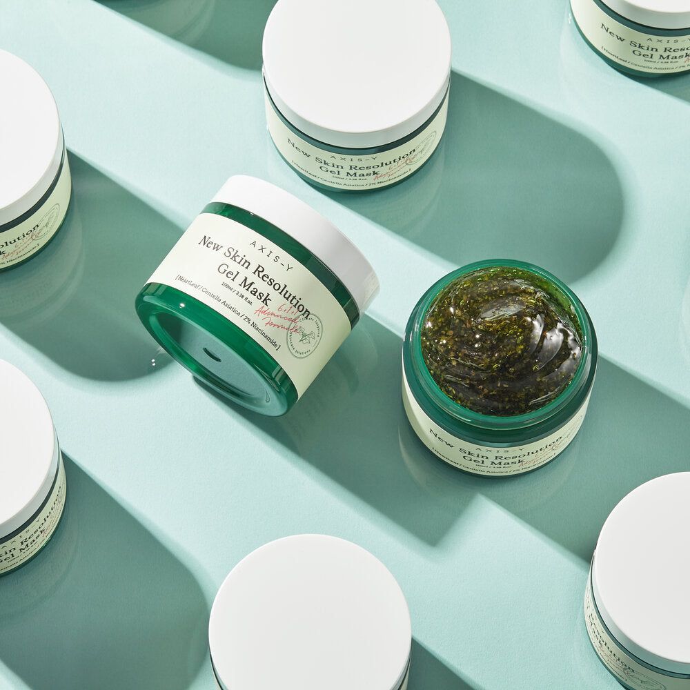 Meerdere groene maskerverpakkingen. Opschrift: New Skin Resolution Gel Mask. Op blauwe achtergrond.