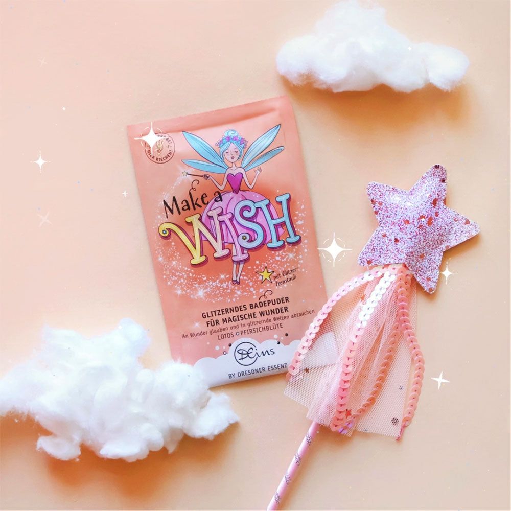 Sachet de bain rose, baguette magique et nuages sur fond rose. Sachet avec impression "Make a Wish". Texte : Poudre de bain scintillante. Marque : Dresdner Essenz.