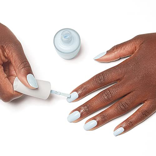 Mains peignant les ongles en bleu clair. Flacon et pinceau de vernis. Processus de manucure.