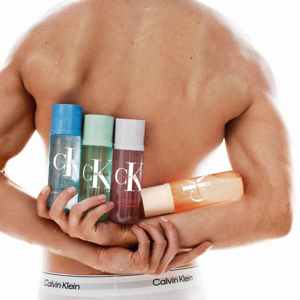 Man houdt vier flessen vast. Opschrift "Calvin Klein". Flessen in blauw, groen, wit en oranje. Man draagt ondergoed met logo.