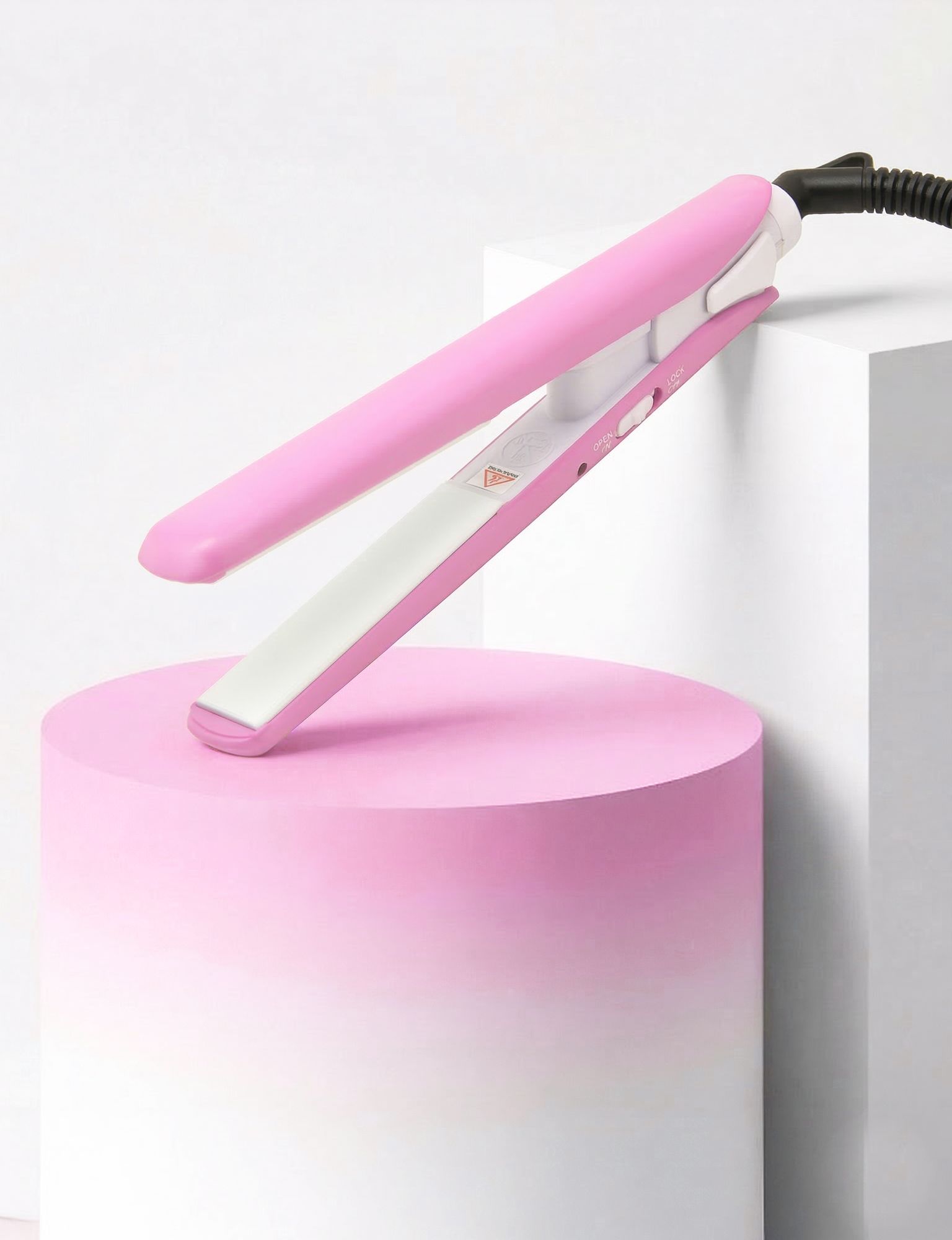 Roze stijltang op roze sokkel. Wit keramisch verwarmingselement. Zwarte kabel. Oplichtend effect.