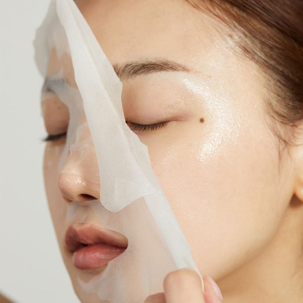 Close-up van een vrouw die een gezichtsmasker aanbrengt. Het masker bedekt een deel van het gezicht. Huid glanzend.