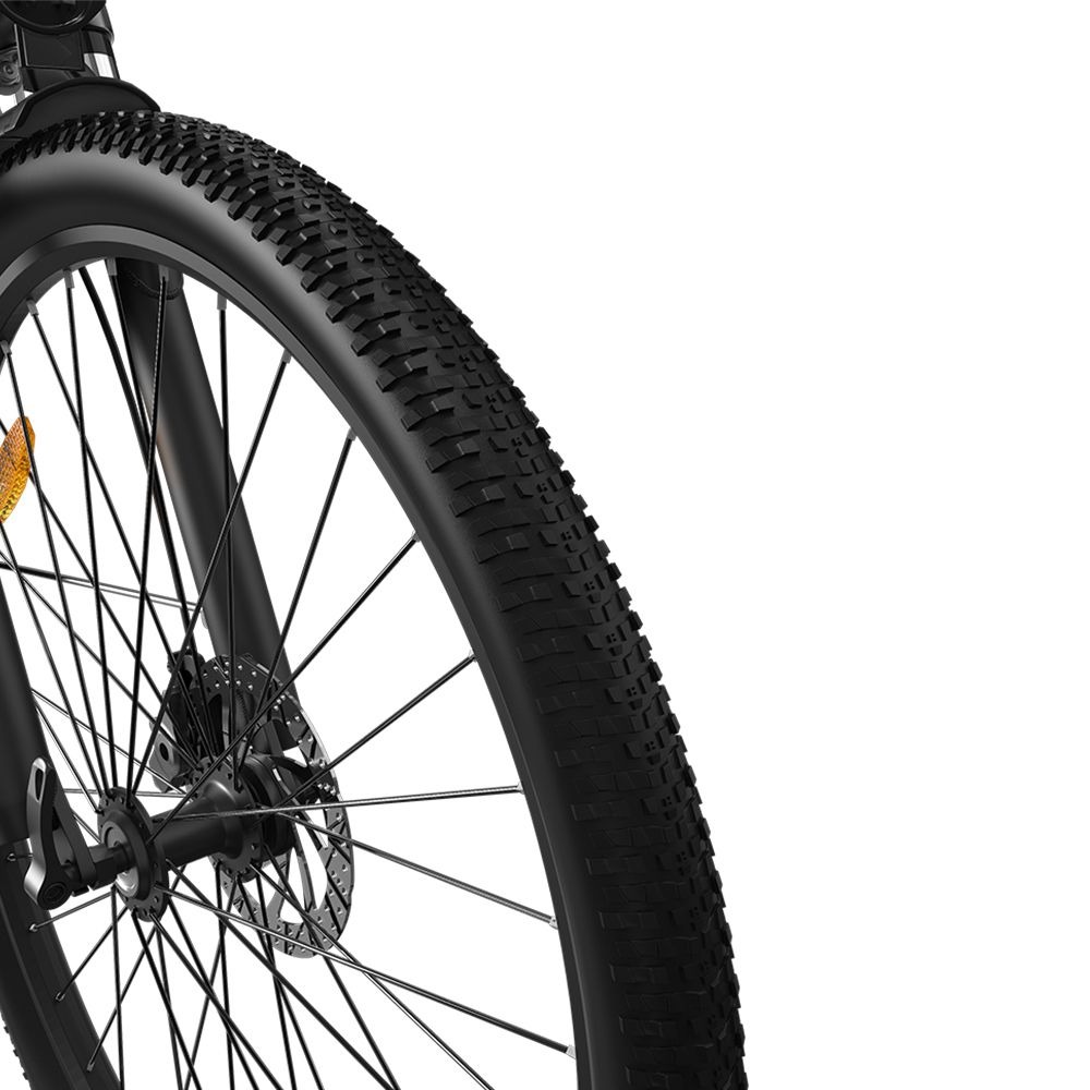 Gros plan sur la roue avant d'un vélo électrique noir. Pneu noir avec profil. Rayons et disque de frein visibles.