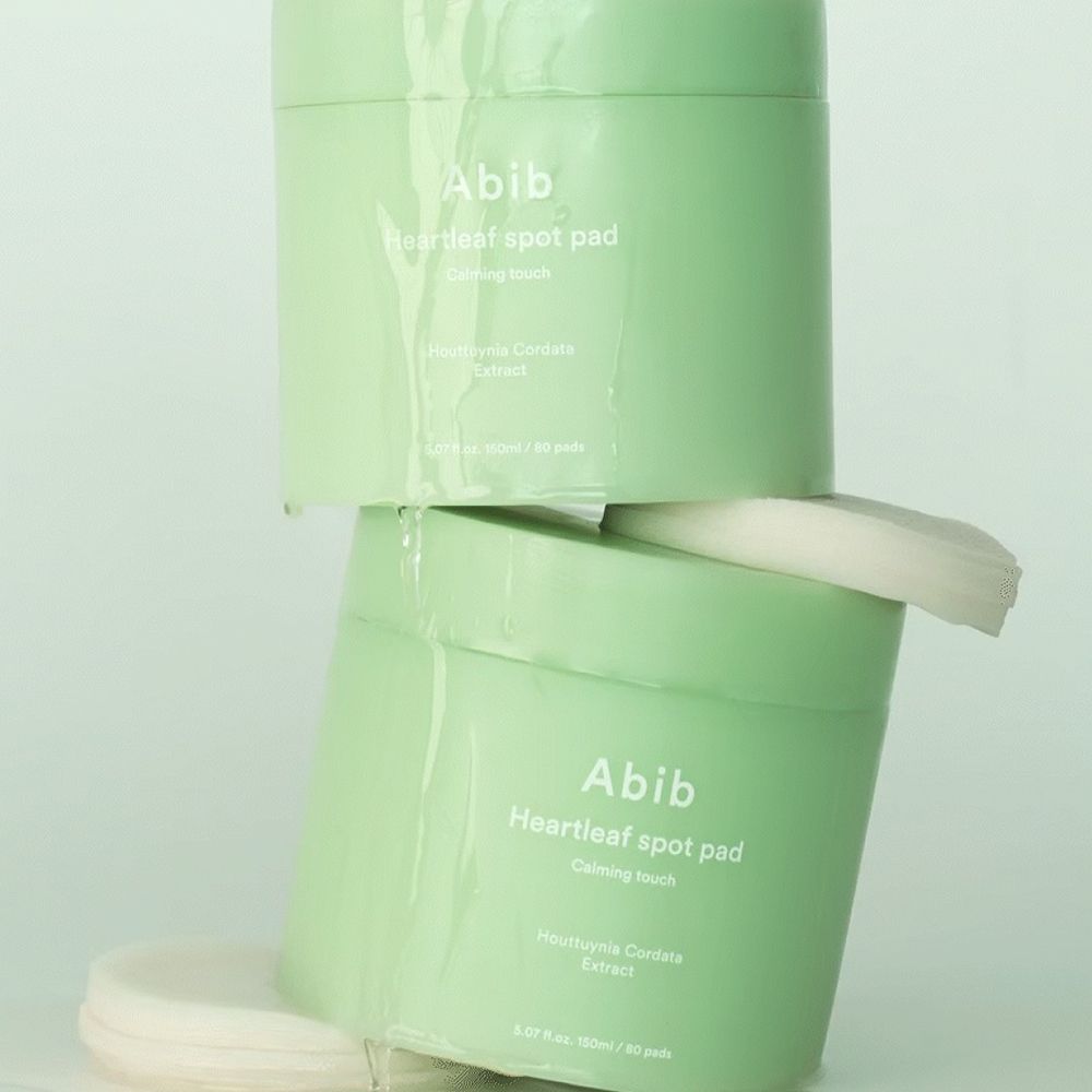 Twee groene potten op elkaar. Opschrift: Abib Heartleaf spot pad. Tekst eronder: Calming touch, Houttuynia Cordata Extract. Pads zichtbaar.