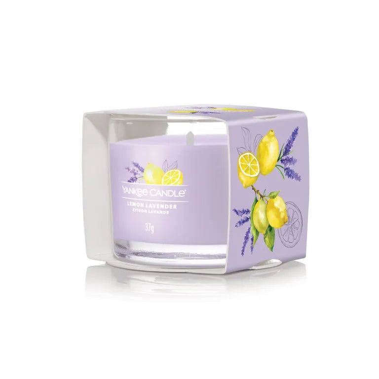 Bougie parfumée en verre dans son emballage. Cire lilas avec impression citron et lavande. Inscription: Lemon Lavender, Citron Lavande, 37g.