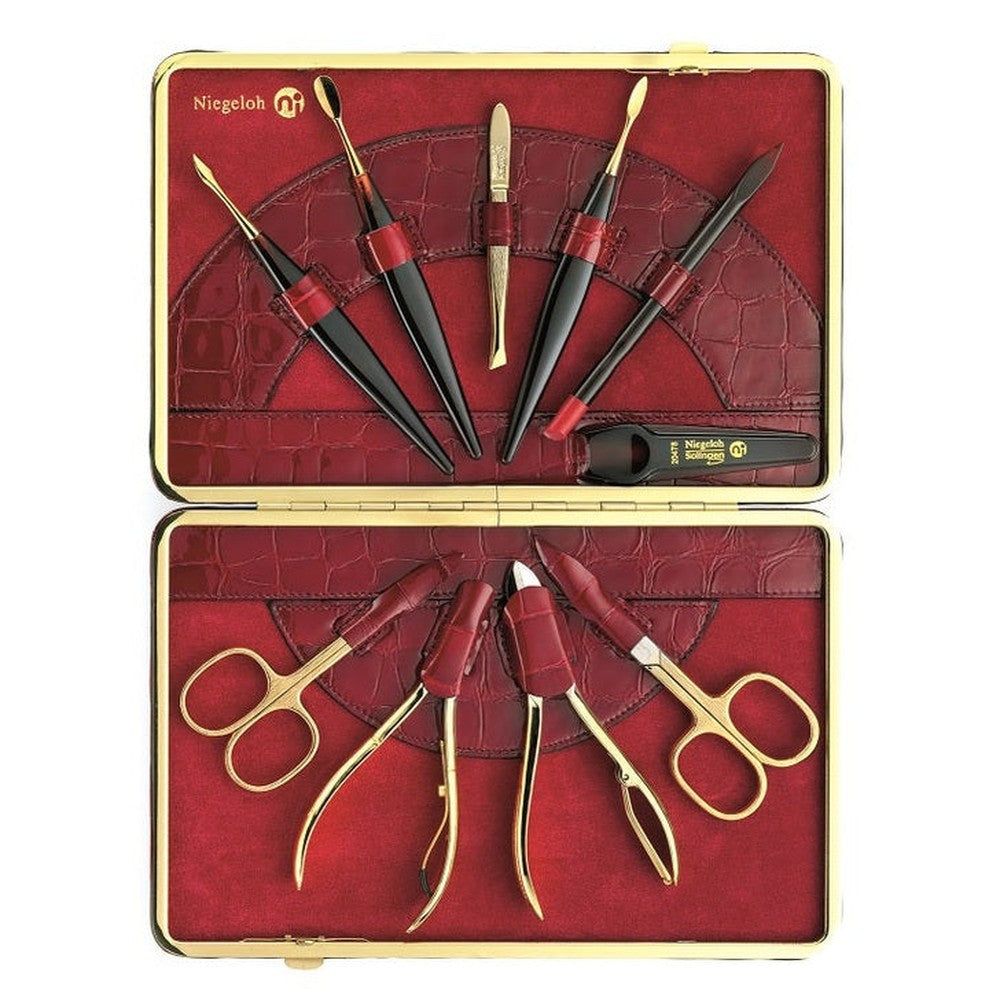 Open rode etui met gouden rand, gevuld met manicuregereedschap. Bevat scharen, cuticle pushers en tangen. Merk Niegeloh.