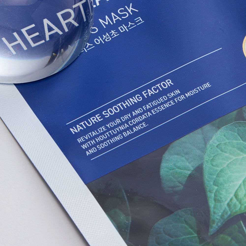 Blauwe verpakking met tekst "NATURE SOOTHING FACTOR" en bladeren. Transparante bol ernaast.