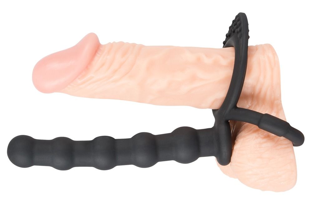 Zwarte penis- en ballenring met anale dildo, bevestigd aan een penis. Ring met nopjes, dildo met ribbels.