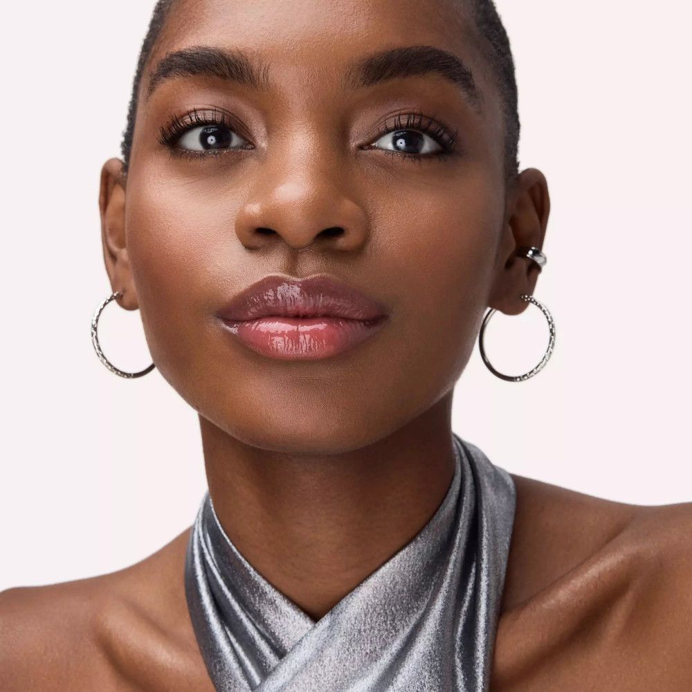 Portret van een vrouw met glanzende lippen. Ze draagt oorbellen.