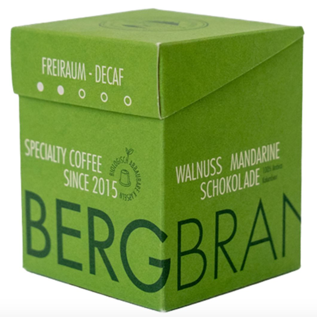 Groene verpakking. Opschrift: BERGBRAND, Freiraum-Decaf, Walnuss Mandarine Schokolade.