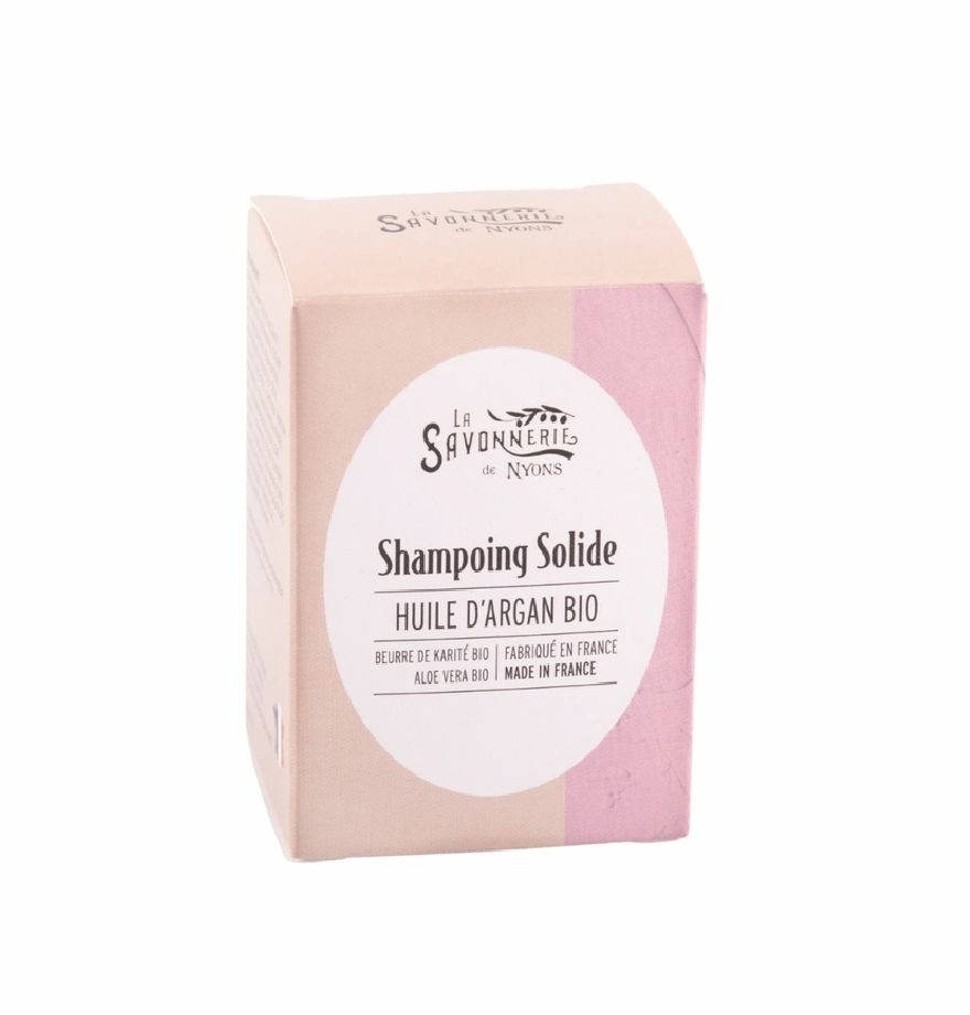 Vaste shampoo in kartonnen verpakking. Roze-beige kleurovergang. Wit etiket met tekst: Huile d'Argan Bio, Made in France.