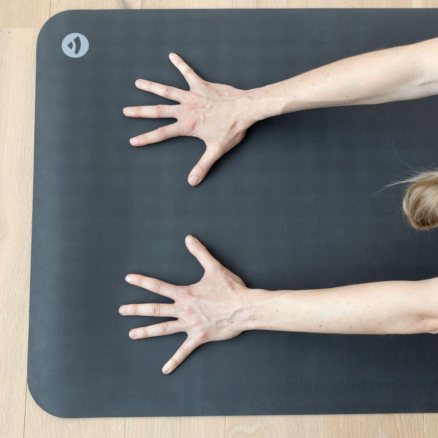 Donkere yogamat met twee handen. Handen met gespreide vingers.