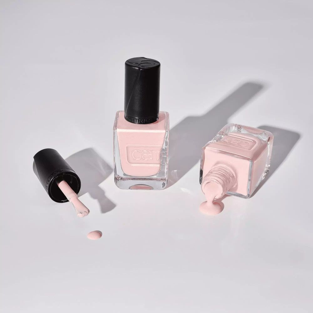 Flacons de vernis à ongles, un ouvert, un renversé. Vernis rose, bouchons noirs. Marque Catrice.