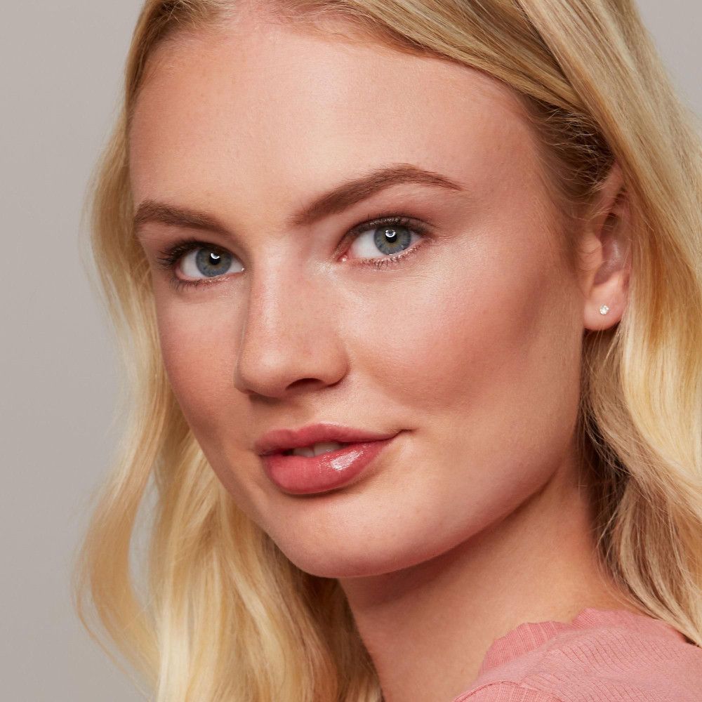 Portrait d'une femme blonde. Elle a les yeux bleus et porte du rouge à lèvres rose. Ses sourcils sont dessinés.