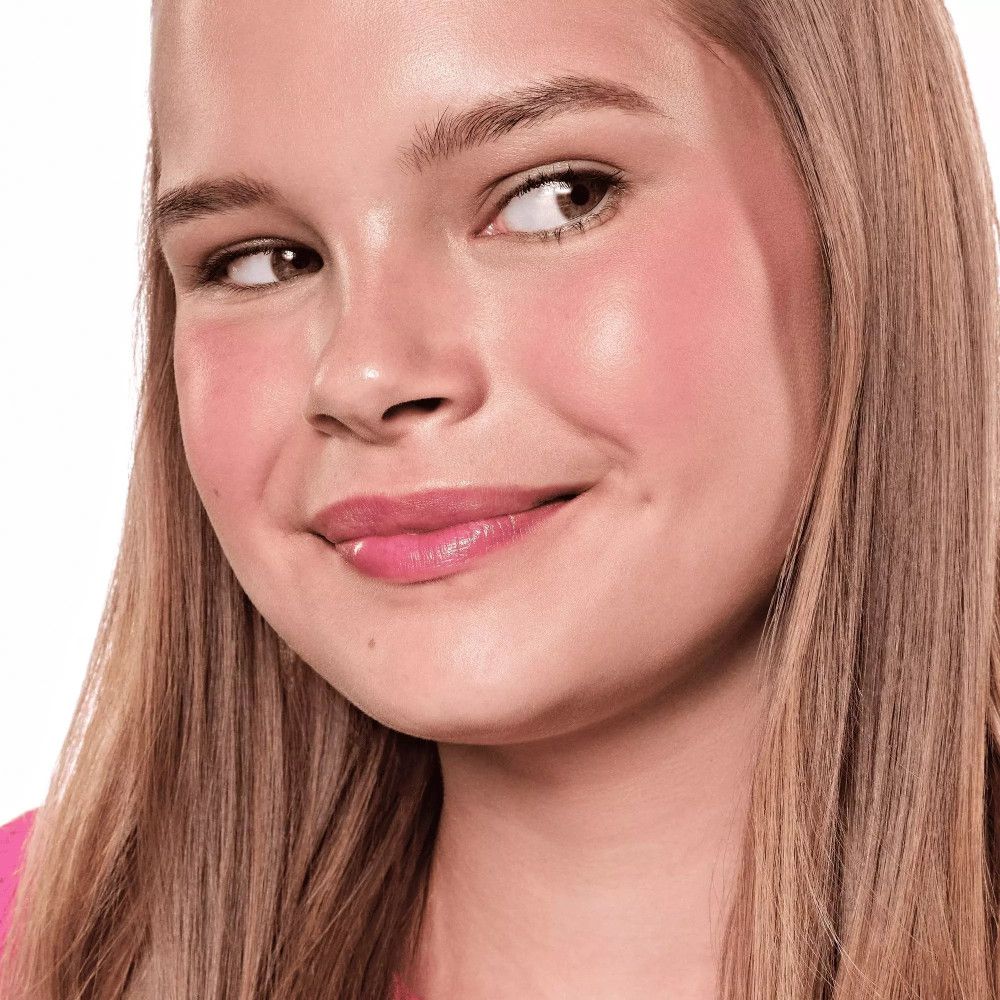 Portrait d'une jeune femme avec du blush sur les joues. Elle sourit et regarde de côté.