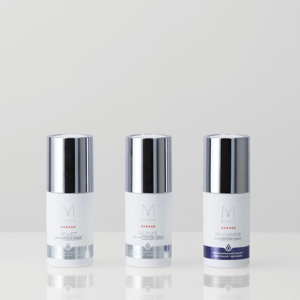 Trois flacons de crème avec bouchons argentés. Inscription: Mylène, Aurage, UP-LIFT, DE-PUFF, RE-CHARGE Eye Contour Cream. Étiquettes blanches.