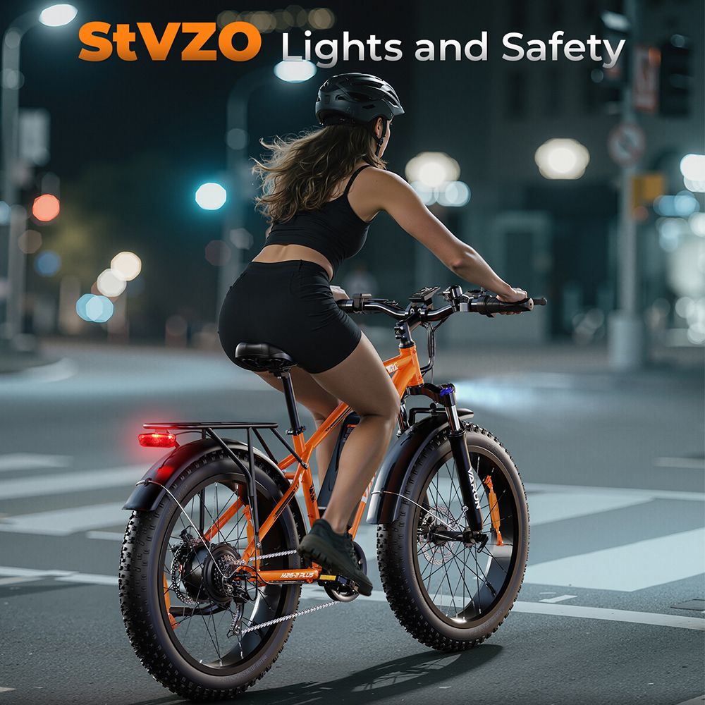 Persoon fietst op een oranje VARUN e-mountainbike 's nachts. StVZO-verlichting. Zwarte kleding, helm.