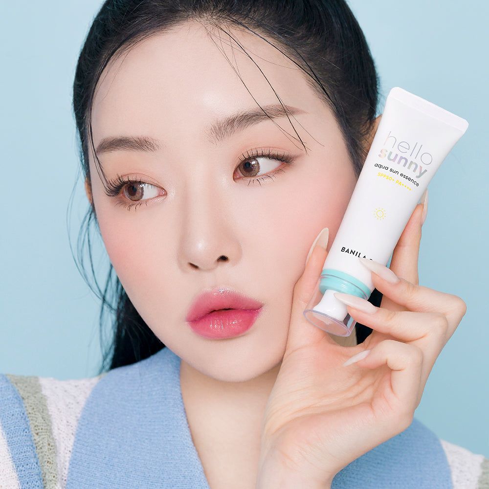 Une femme tient BANILA CO Hello Sunny Aqua Sun Essence SPF50+ PA++++.