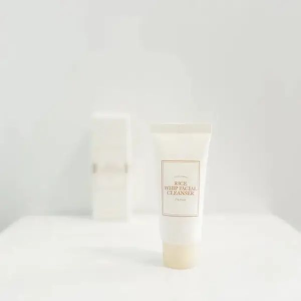 Tube blanche avec l'inscription "Rice Whip Facial Cleanser". Derrière, un récipient rectangulaire. Les deux sur fond blanc.