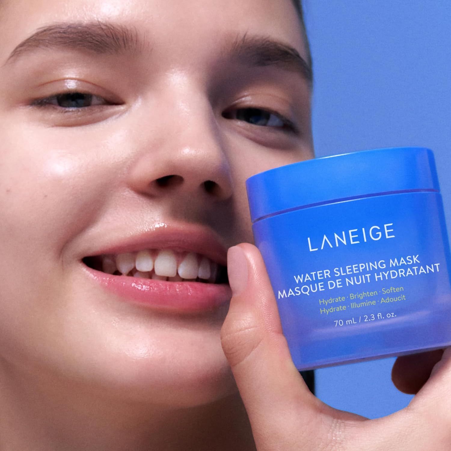 Femme tenant un pot bleu avec texte blanc: LANEIGE, WATER SLEEPING MASK. La femme sourit.