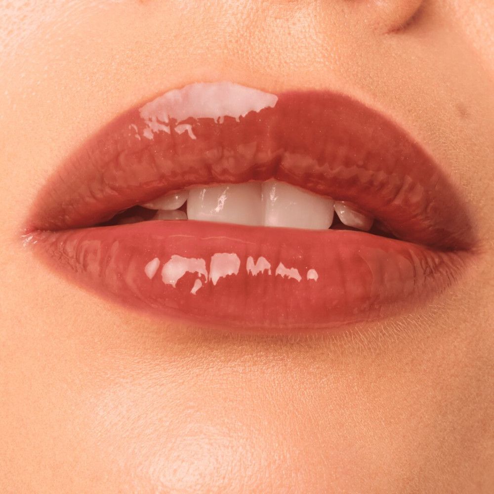 Close-up van lippen met glanzende lipgloss. De lippen zijn roodbruin.
