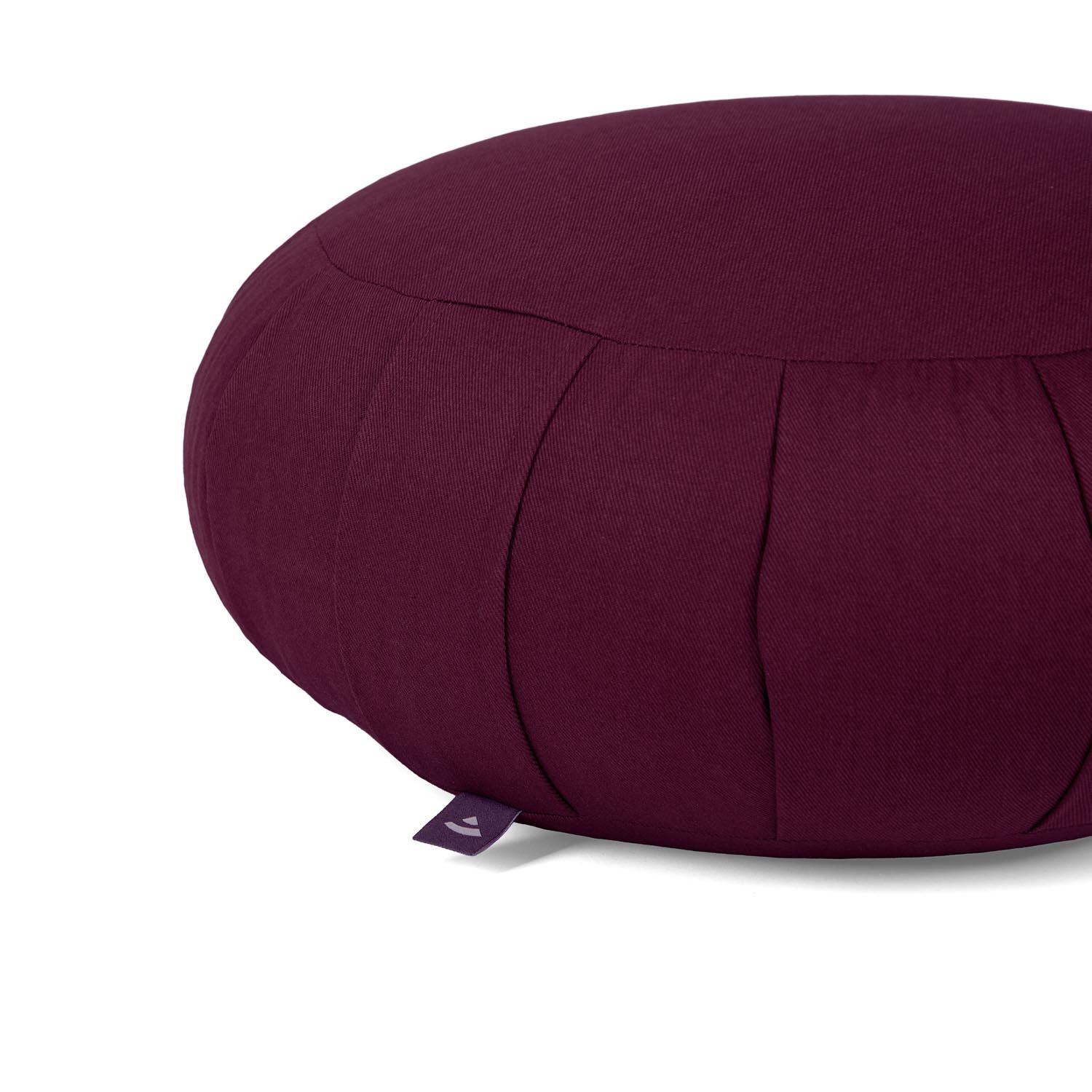 Gros plan sur un coussin de méditation ZAFU bordeaux. Plis, étiquette. Sur fond clair.