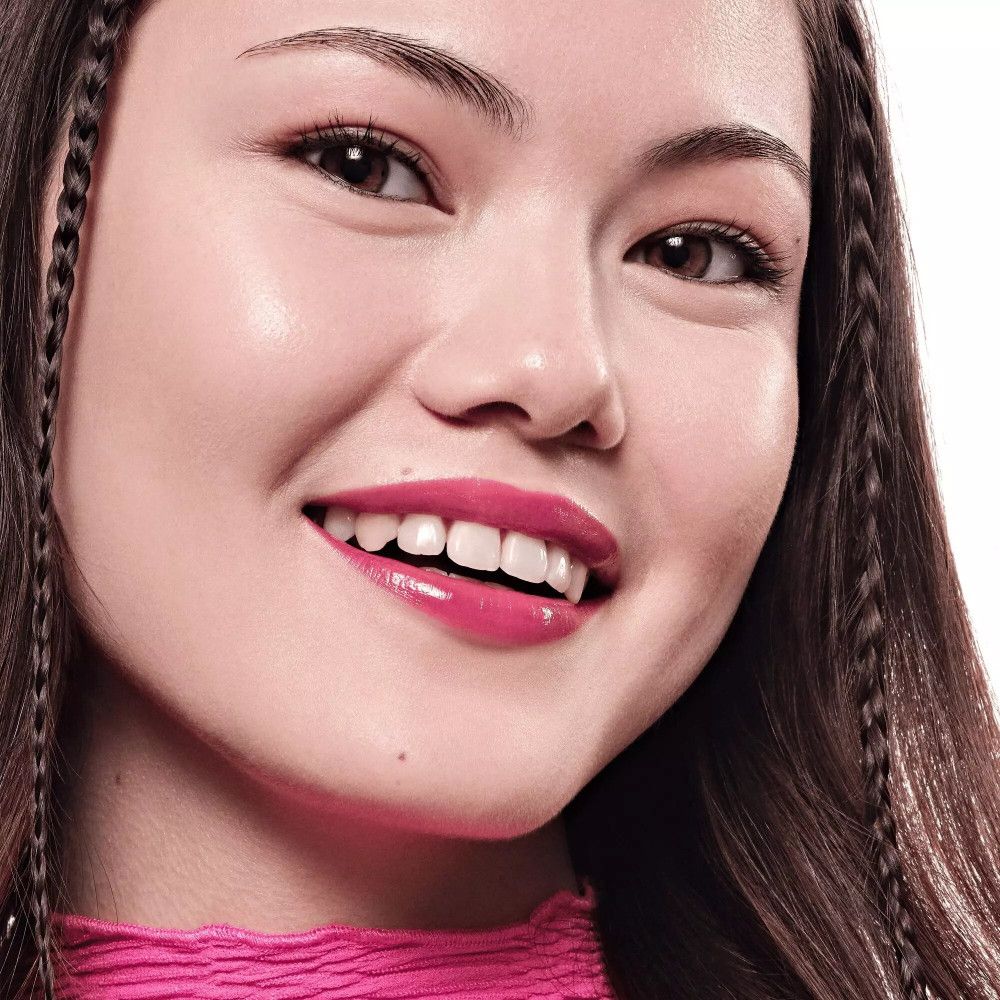 Portrait d'une femme avec un Lip Tint rose. Elle sourit. Cheveux brun foncé.