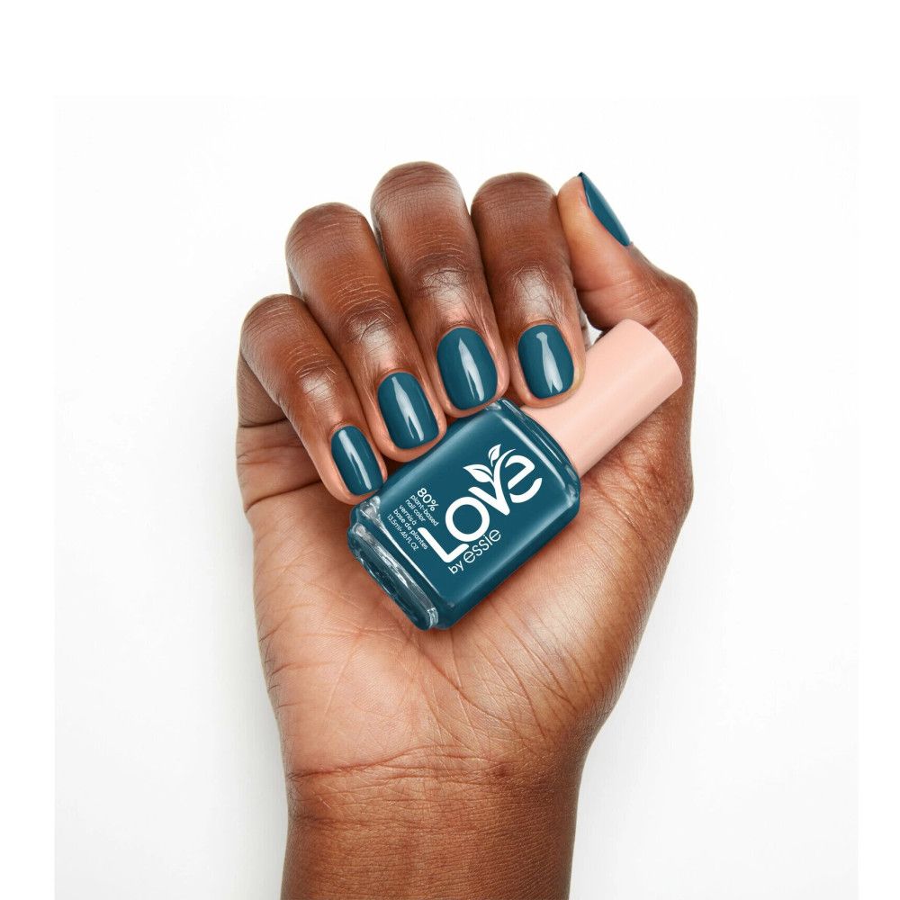 Hand met gelakte nagels en nagellakflesje. Flesje met opschrift 'Love by essie'.