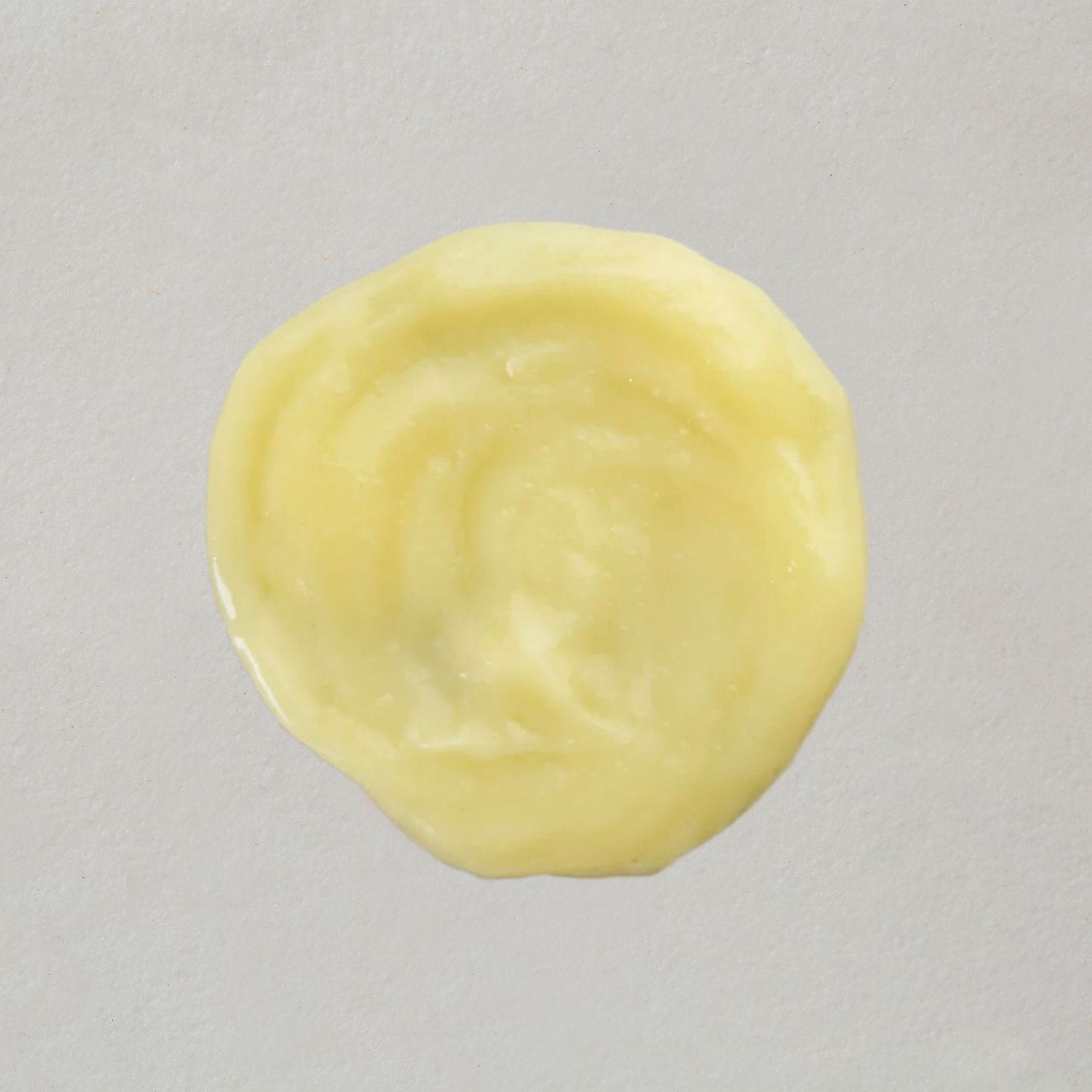 Une petite quantité de revitalisant capillaire crémeux et jaune sur fond clair.