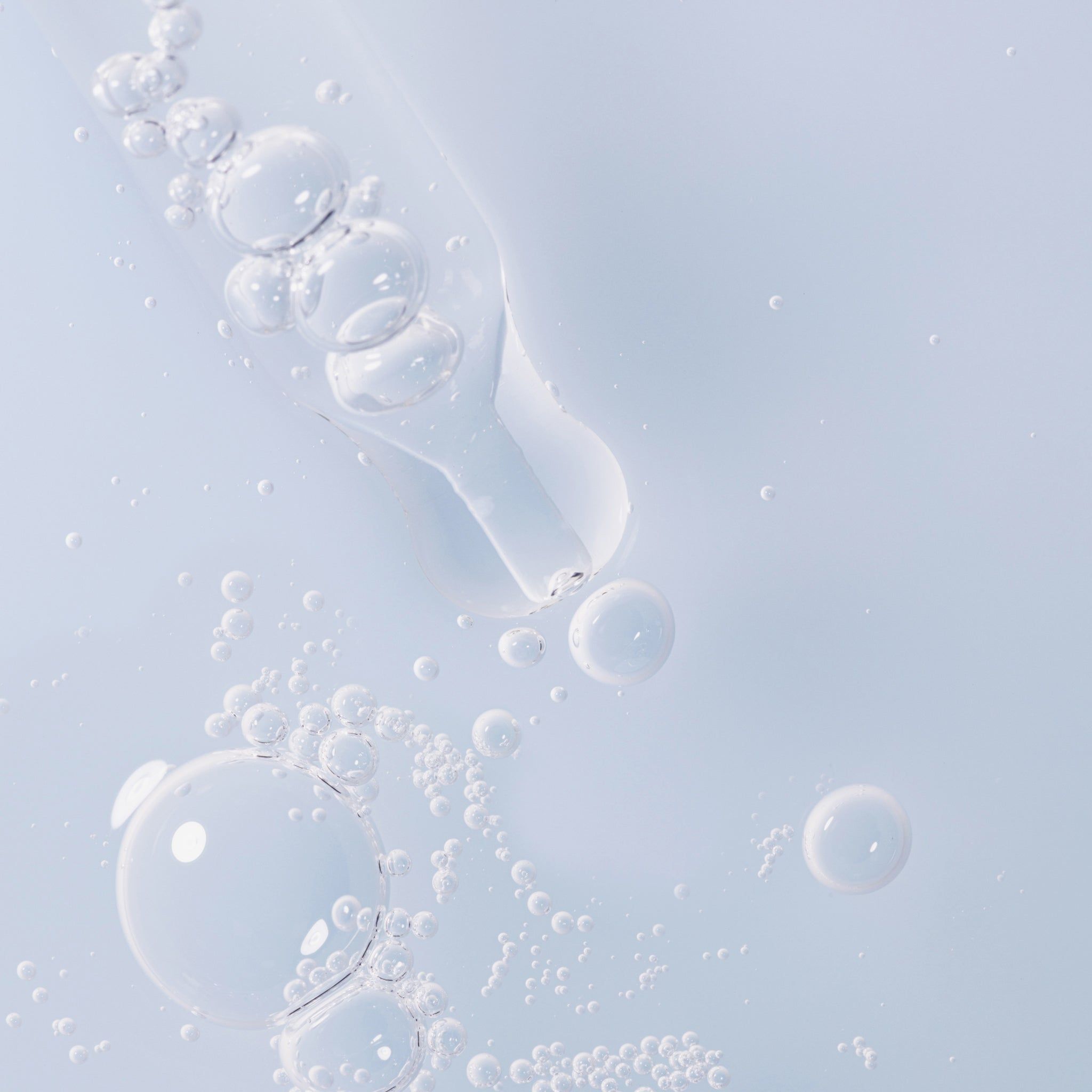 Gros plan sur des bulles de sérum. Pipette avec gouttelettes de sérum. Liquide bleu clair.