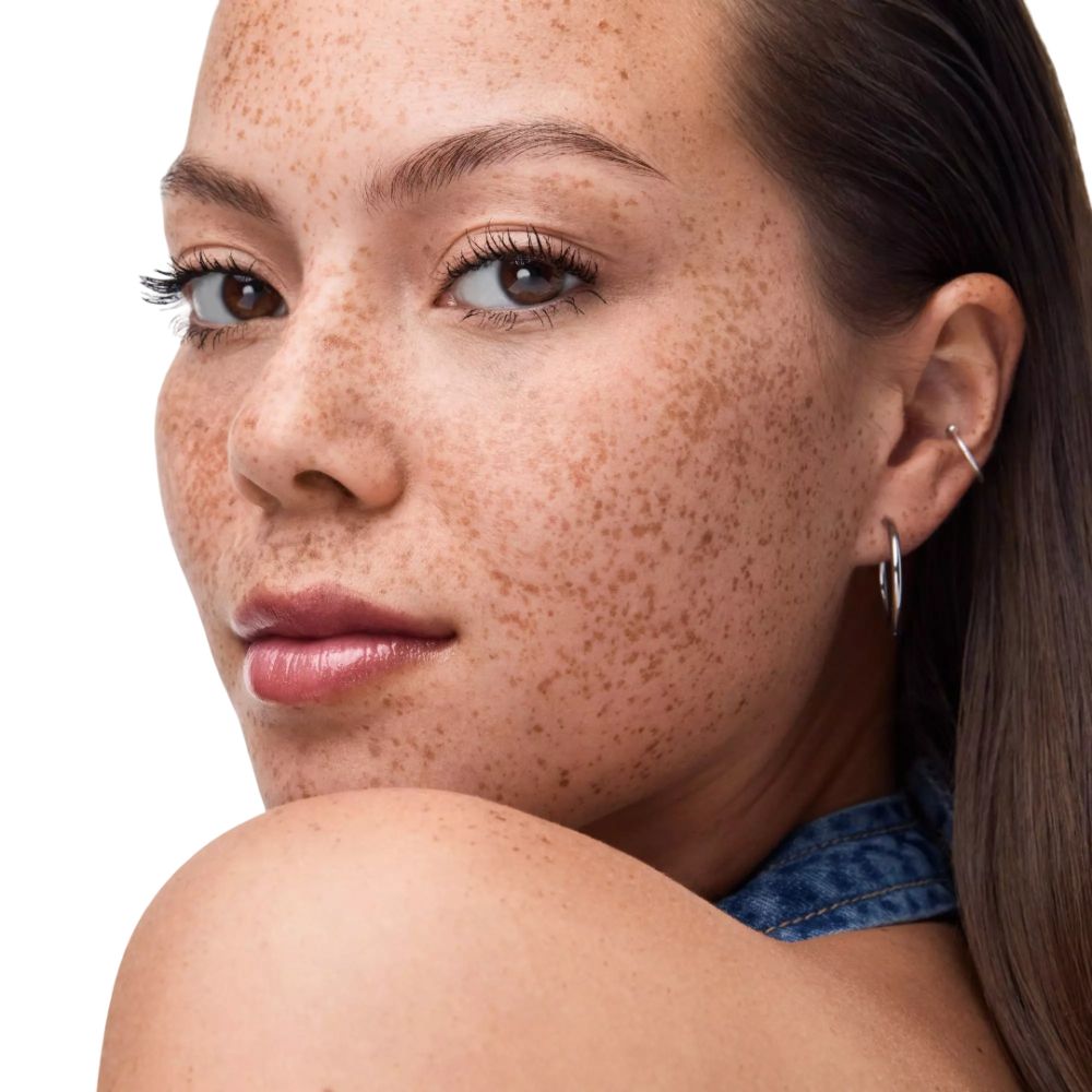 Portret van een vrouw met sproeten. Ze draagt lippenstift. Kijkt naar de camera.