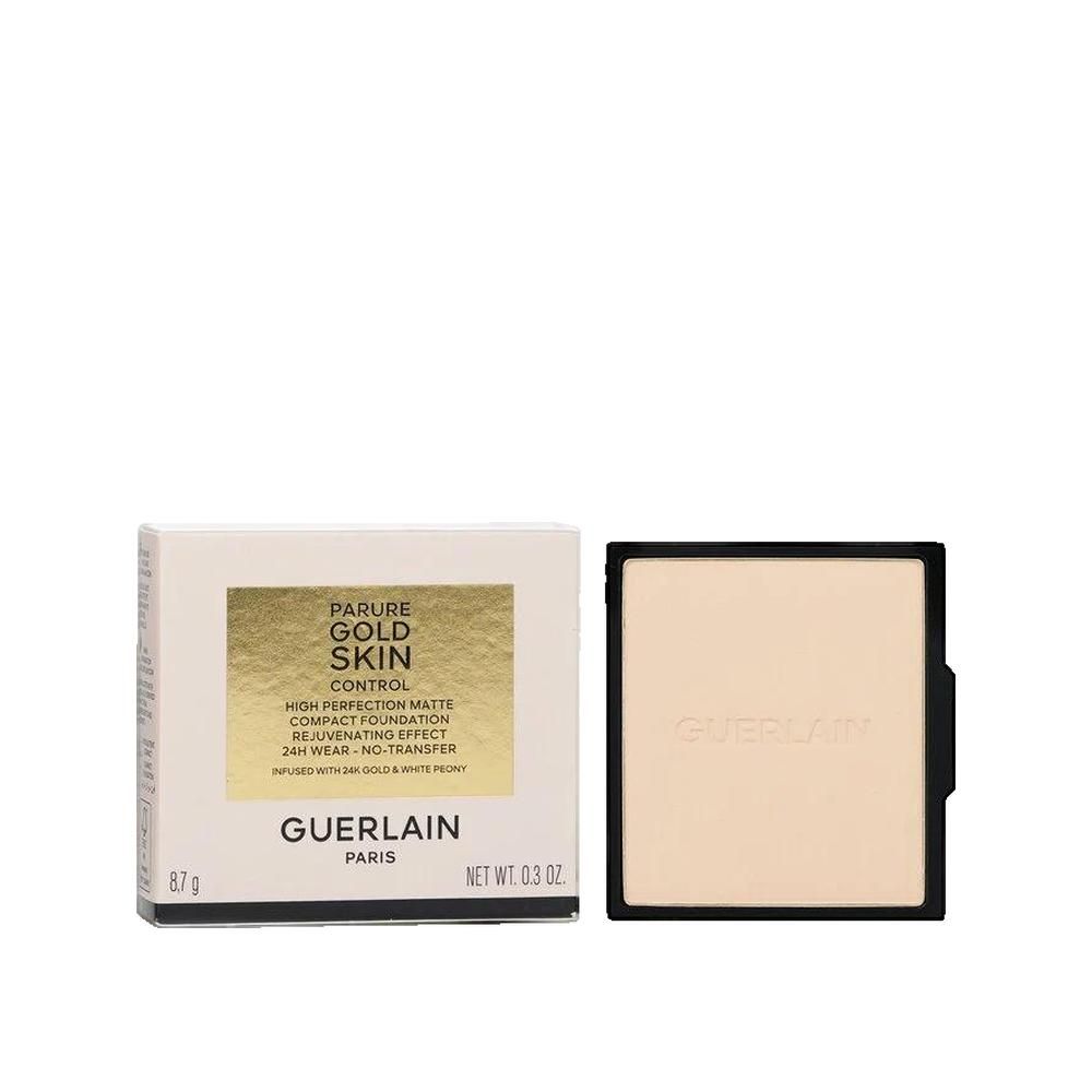 Fond de teint compact et emballage. Boîte blanche avec texte doré. Fond de teint compact noir. Inscription: Parure Gold Skin Control.
