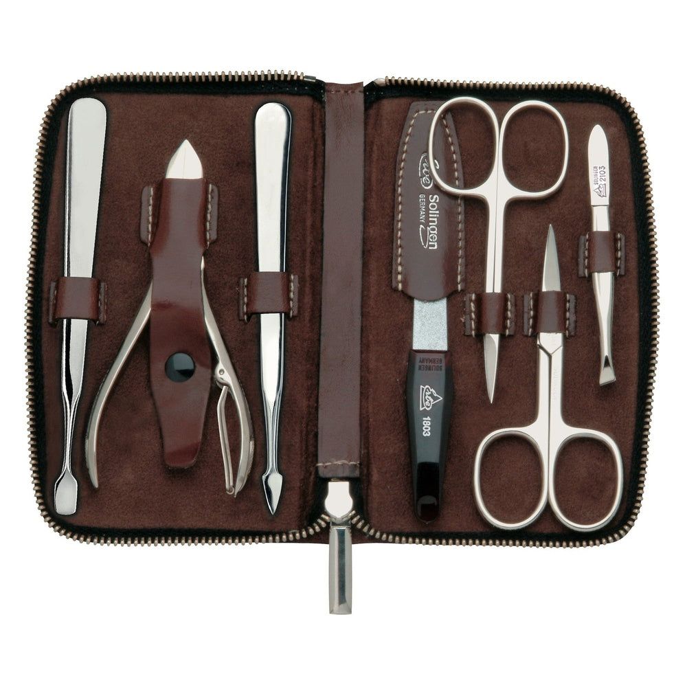 Hoogwaardige manicure etui van bruin leer met 7 gepolijste roestvrijstalen instrumenten voor nagelverzorging.