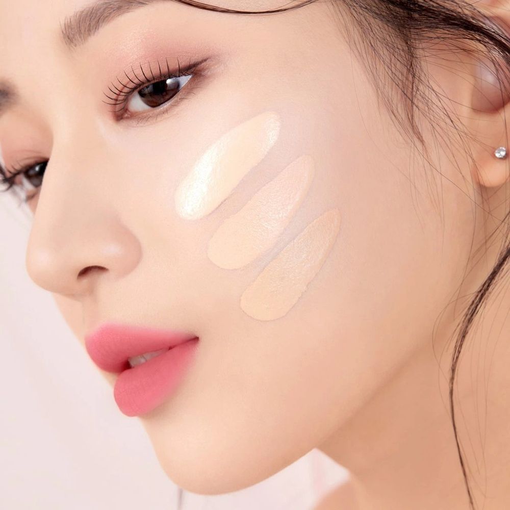 Trois teintes de BLACK ROUGE Thin Layer Velour Cushion Foundation appliquées sur le visage d'une femme.